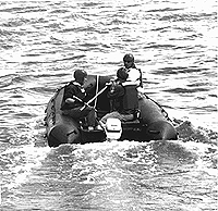 Whale rescue teams attach special cutting tools to long extension poles so that they can reach fishing gear on an entangled whale from an inflatable raft. (From left) Todd Sollows, Ed Lyman and Stormy Mayo used the specialized tools during a June 5 disentanglement in the Bay of Fundy.